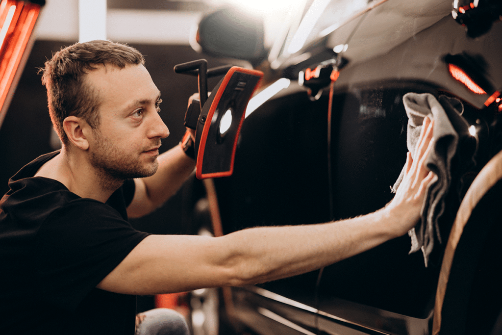 Un homme nettoie une voiture noire.